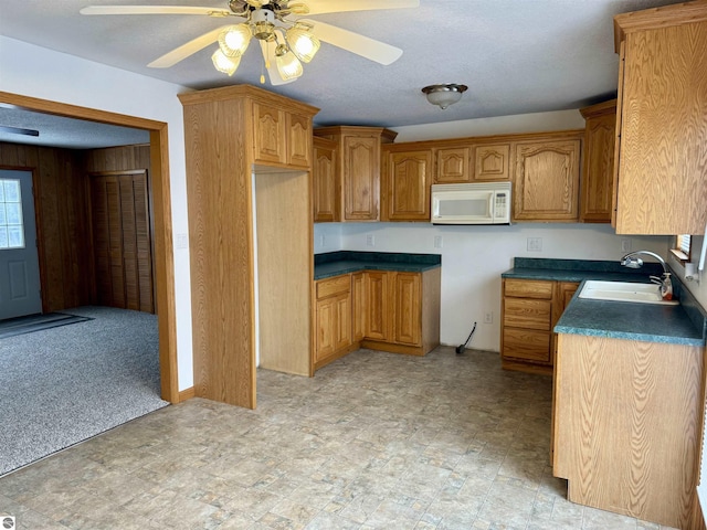 kitchen with wood walls, ceiling fan, and sink