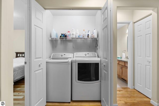 clothes washing area featuring independent washer and dryer and light hardwood / wood-style flooring