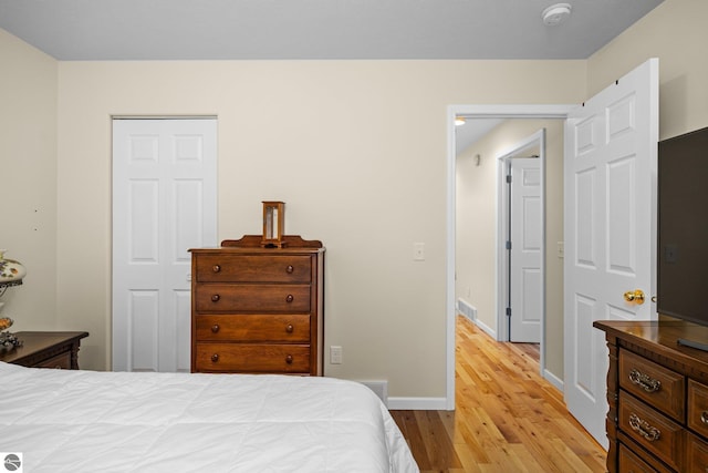 bedroom with light hardwood / wood-style floors and a closet