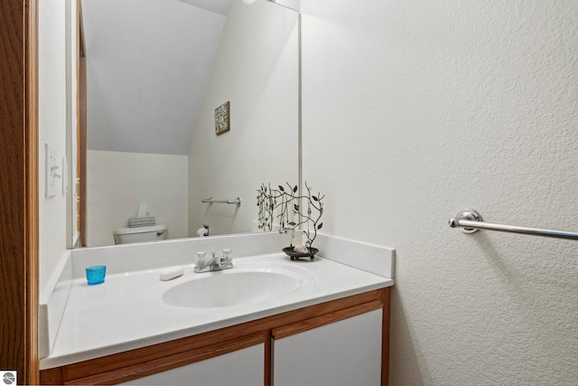 bathroom with toilet, vanity, and vaulted ceiling