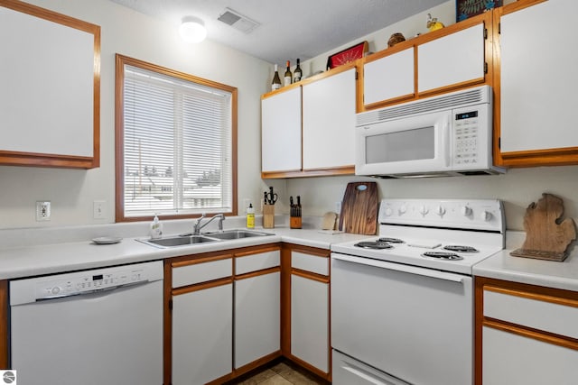 kitchen featuring white appliances, white cabinetry, and sink