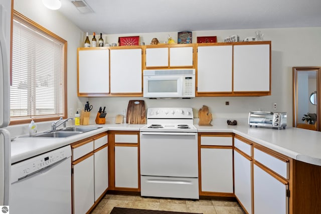 kitchen featuring white appliances, white cabinets, light tile patterned flooring, and sink