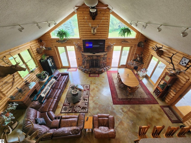 living room featuring high vaulted ceiling, a textured ceiling, log walls, and a stone fireplace