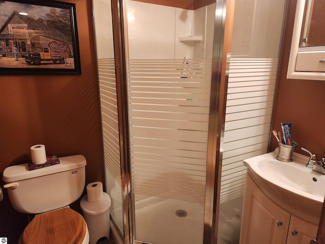 bathroom featuring toilet, a shower with door, and vanity