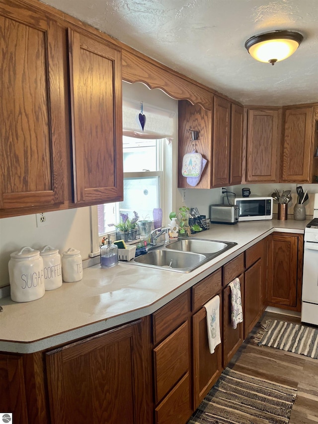 kitchen featuring white appliances, dark hardwood / wood-style flooring, a textured ceiling, and sink