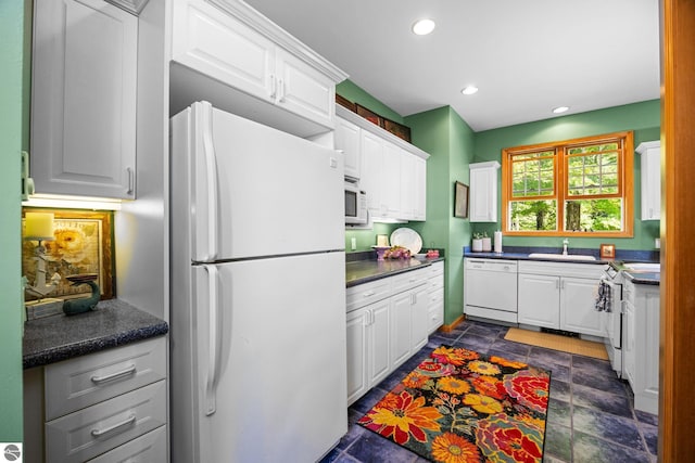 kitchen with sink, white appliances, and white cabinetry