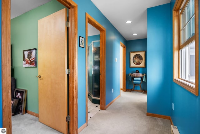 corridor with a baseboard heating unit and light colored carpet