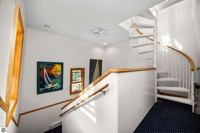 stairs featuring wood walls, ceiling fan, and carpet