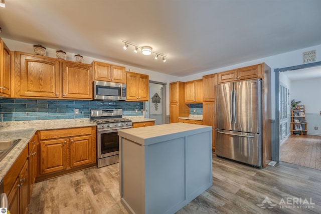 kitchen featuring light hardwood / wood-style flooring, stainless steel appliances, tasteful backsplash, a kitchen island, and sink