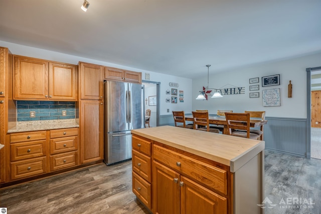 kitchen with stainless steel fridge, wood counters, pendant lighting, and dark hardwood / wood-style floors