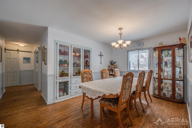 dining room with a notable chandelier, a barn door, and hardwood / wood-style floors