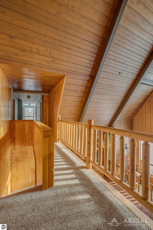 hall with carpet flooring, wood walls, lofted ceiling with beams, and wood ceiling