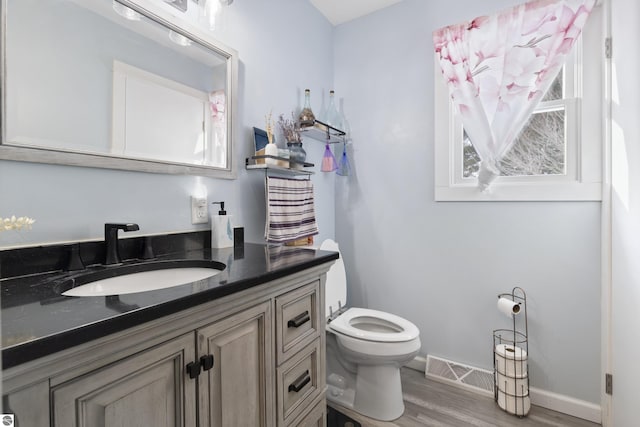 bathroom with toilet, vanity, and wood-type flooring