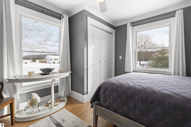 bedroom with ceiling fan, multiple windows, hardwood / wood-style flooring, and crown molding