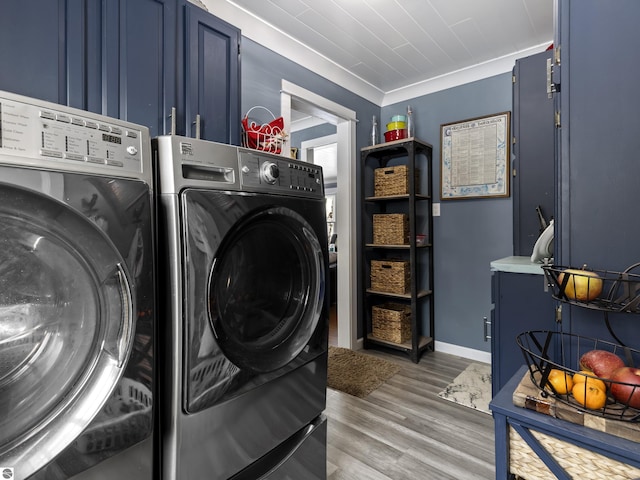 clothes washing area featuring cabinets, separate washer and dryer, crown molding, and hardwood / wood-style flooring