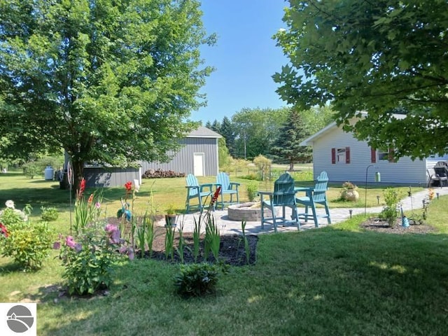 view of yard with a patio, a fire pit, and an outdoor structure