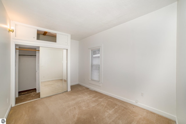 unfurnished bedroom with a closet and light colored carpet