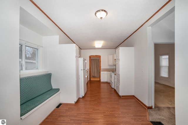 hall featuring light wood-type flooring and a textured ceiling