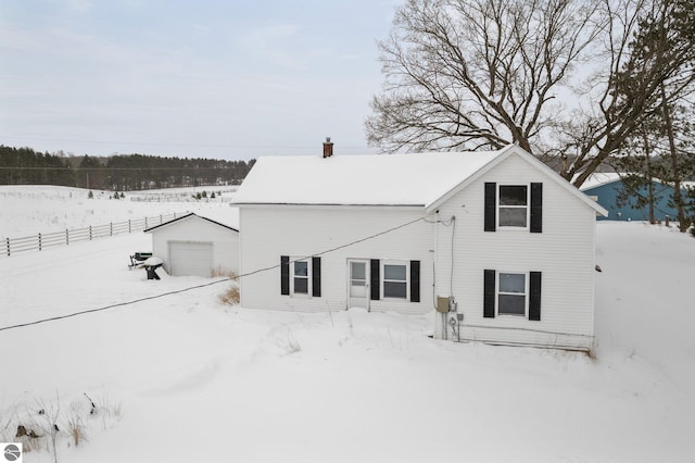 snow covered back of property with an outbuilding and a garage