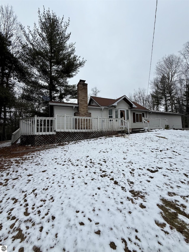 snow covered rear of property with a wooden deck