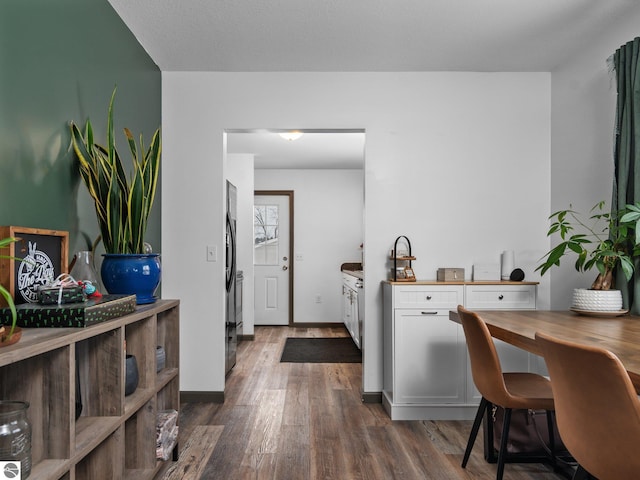 kitchen featuring dark hardwood / wood-style flooring, white cabinetry, and black fridge