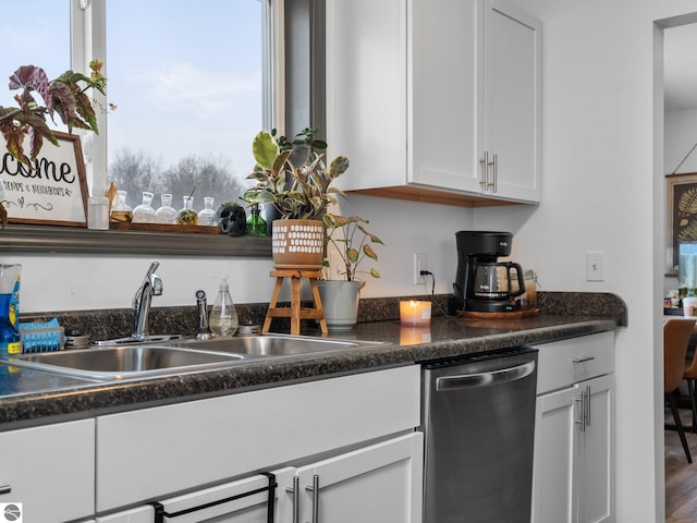 kitchen featuring hardwood / wood-style flooring, stainless steel dishwasher, white cabinets, and sink