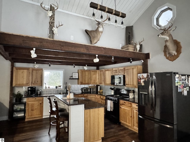 kitchen featuring beam ceiling, a breakfast bar, black appliances, and a center island