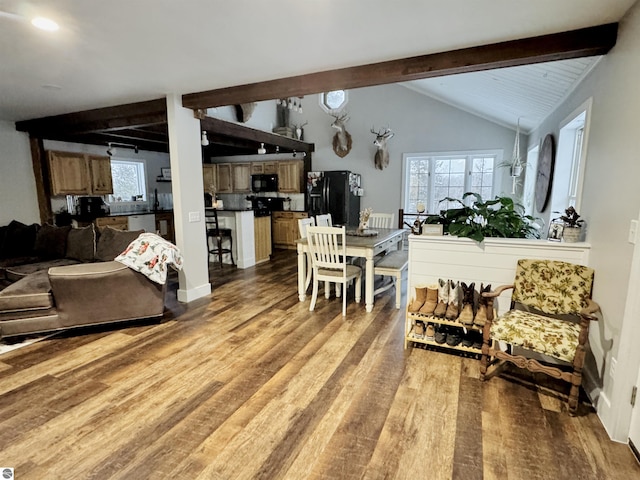 dining area with hardwood / wood-style flooring and vaulted ceiling with beams