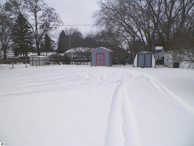 yard layered in snow featuring a storage shed