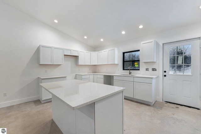 kitchen featuring vaulted ceiling, a center island, sink, white cabinetry, and light stone countertops