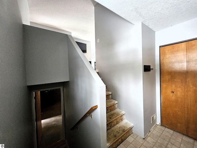 stairs featuring a textured ceiling