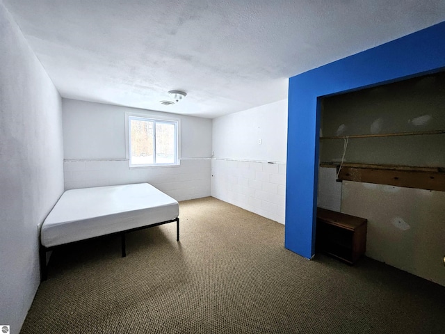 unfurnished bedroom featuring a textured ceiling and dark colored carpet