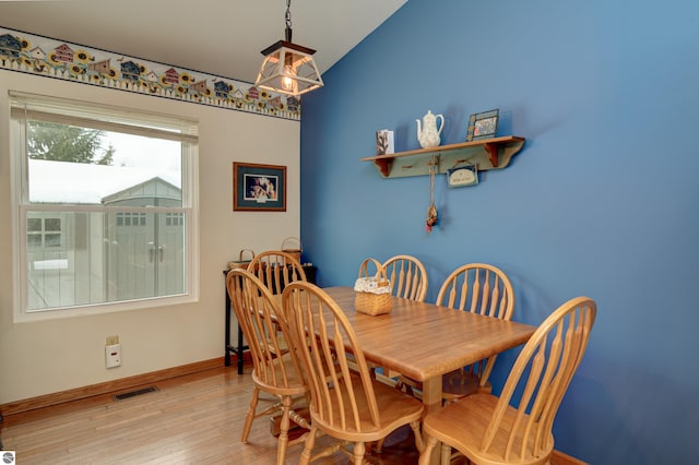 dining room featuring vaulted ceiling and light hardwood / wood-style flooring