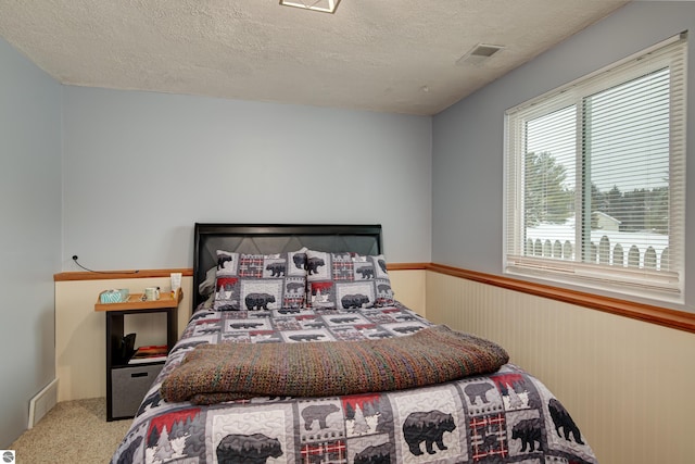 bedroom featuring carpet floors, a textured ceiling, and wood walls