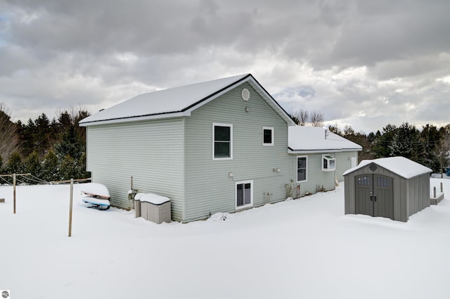 snow covered house featuring a shed