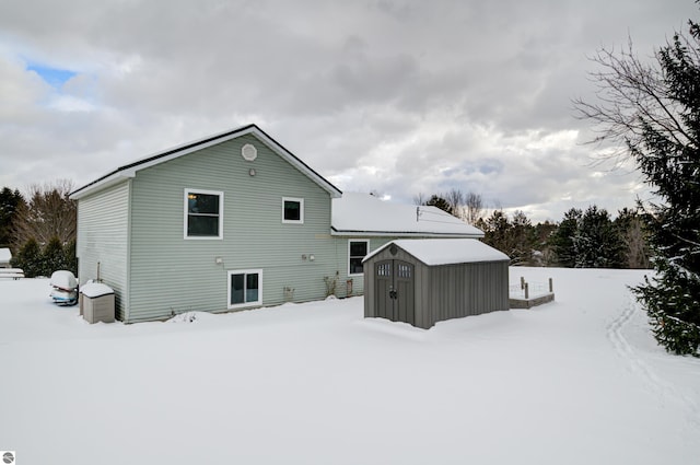 snow covered rear of property with a storage shed