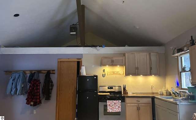 kitchen with vaulted ceiling, sink, stainless steel range with gas stovetop, black refrigerator, and light brown cabinetry