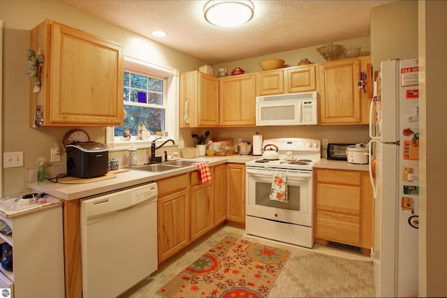 kitchen featuring light brown cabinetry, sink, white appliances, and a textured ceiling