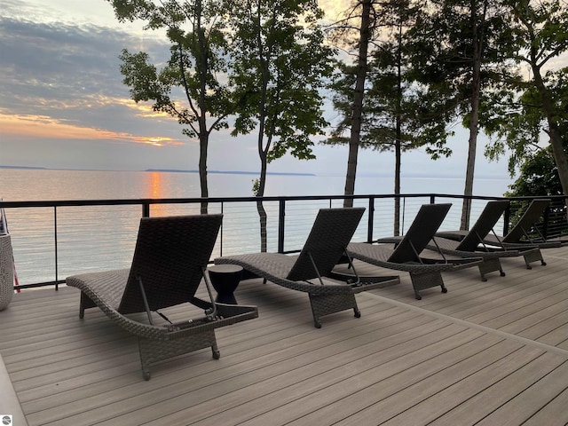 deck at dusk featuring a water view