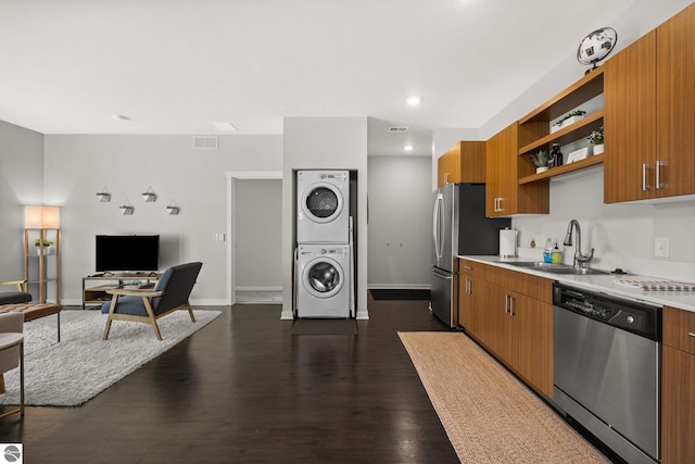 kitchen with dark wood-type flooring, sink, appliances with stainless steel finishes, and stacked washing maching and dryer