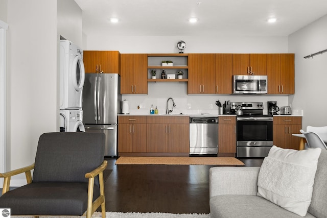 kitchen featuring stacked washing maching and dryer, appliances with stainless steel finishes, sink, and dark hardwood / wood-style flooring