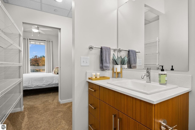 bathroom with ceiling fan, a paneled ceiling, and vanity