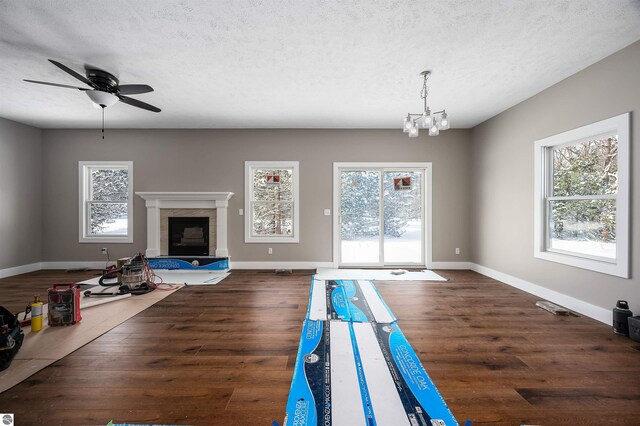 interior space featuring ceiling fan with notable chandelier, a textured ceiling, and dark hardwood / wood-style flooring