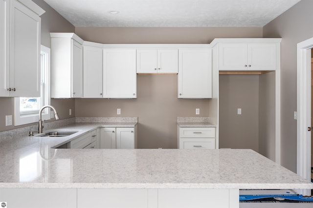 kitchen featuring white cabinetry, sink, and light stone counters