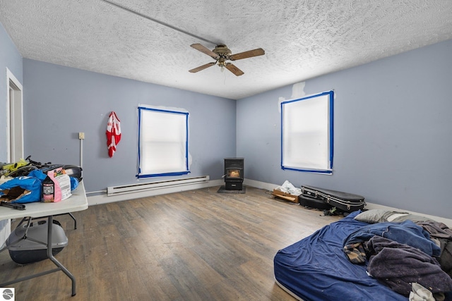 interior space with ceiling fan, hardwood / wood-style floors, a wood stove, a textured ceiling, and a baseboard radiator