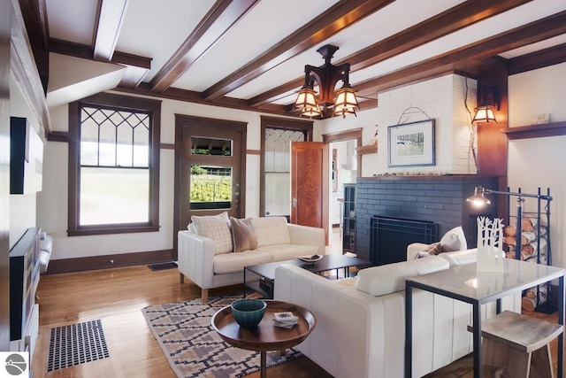 living room with beam ceiling, light wood-type flooring, and a fireplace