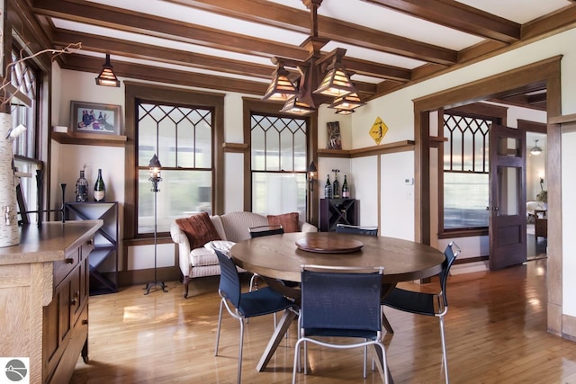 dining room with a notable chandelier, beamed ceiling, and light wood-type flooring