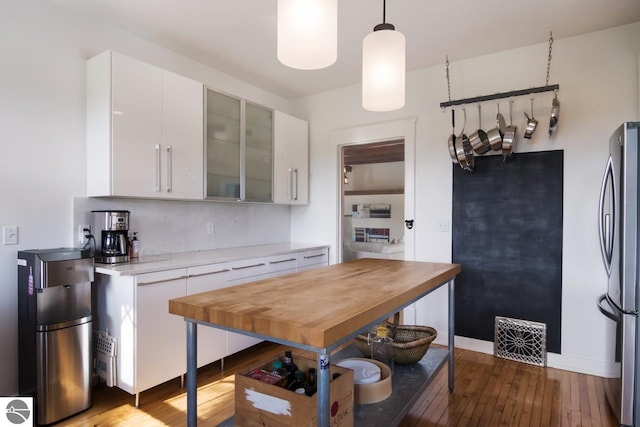 kitchen with decorative backsplash, stainless steel refrigerator, white cabinetry, and pendant lighting