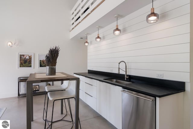 kitchen with stainless steel dishwasher, decorative light fixtures, sink, and white cabinetry