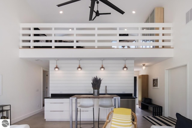 kitchen featuring hanging light fixtures, white cabinets, and a towering ceiling